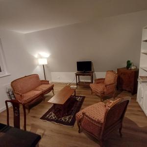 un soggiorno con sedie, tavolo e TV di Les vignobles d'Alsace a Wintzenheim