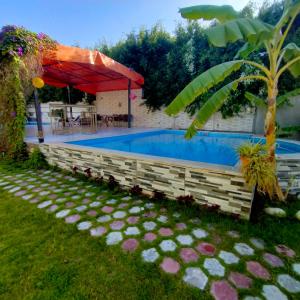 a swimming pool in a yard with a red umbrella at Two pools private villa for families. in Qaryat Shākūsh