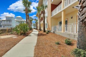 a sidewalk in front of a building with palm trees at Waterside Village Condo 302 in Mexico Beach