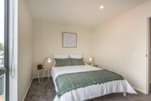 een witte slaapkamer met een bed en een raam bij Hop, Skip, Jump to the city ! in Christchurch