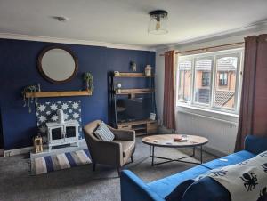 a blue living room with a couch and a table at Nautical nook, East Yorkshire two bed flat, free parking and WiFi in Hull