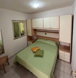 Dormitorio pequeño con cama verde y armarios blancos en Villa Angela case vacanza, en Vieste