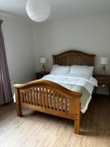 - un lit en bois dans une chambre avec deux lampes dans l'établissement Teach Róise, à Dunfanaghy
