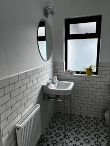 La salle de bains blanche est pourvue d'un lavabo et d'un miroir. dans l'établissement Teach Róise, à Dunfanaghy