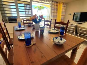 einem Holztisch mit Tellern und blauen Gläsern darauf in der Unterkunft Ocean front Vacation home near el Rain forest in Luquillo