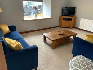 a living room with two blue chairs and a coffee table at The Granary at Tinto Retreats, Biggar is a gorgeous 3 bedroom Stone cottage in Wiston