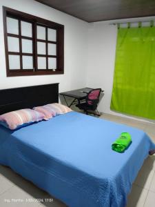 een slaapkamer met een blauw bed met een groene handdoek erop bij Casa Hotel El Cafetal in Cumaral
