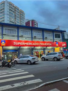 una calle con coches aparcados frente a una tienda en Ap Canto do Forte com Wi-Fi, TV e varanda, en Praia Grande