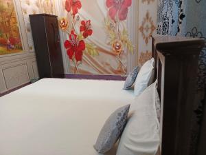 a bedroom with a white bed with a flower wallpaper at Al Madina Guest House in Hyderabad