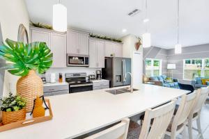 uma cozinha com armários brancos e uma grande ilha com uma planta em Stunning 5BR Home - Family Resort - Private Pool and BBQ! em Kissimmee