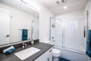 a white bathroom with a sink and a shower at L'Austin Rêve by Revelstoke Vacations in Revelstoke +11 photos