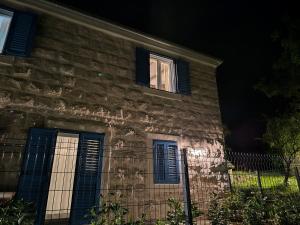 uma casa de pedra com janelas azuis fechadas à noite em Villa Antika em Velika Cista