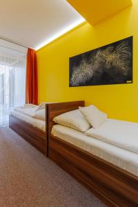 2 łóżka w pokoju z żółtą ścianą w obiekcie Hostel Mayer Superior Veszprém w mieście Veszprém