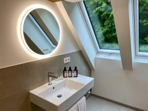 La salle de bains est pourvue d'un lavabo et de 2 fenêtres. dans l'établissement schlossmühle - lean luxury boutique hotel, à Glottertal