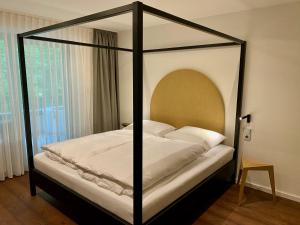 a bedroom with a canopy bed with white sheets at schlossmühle - lean luxury boutique hotel in Glottertal