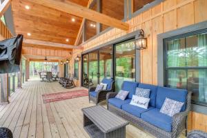 a porch with a blue couch on a wooden house at Gorgeous Drasco Home Near Greers Ferry Lake! in Heber Springs