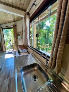 a kitchen with a sink and a large window at chalés frente à praia in Trindade