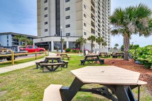 a group of picnic tables in a park with a building at Mod Myrtle Beach Resort Condo with Beach Access in Myrtle Beach