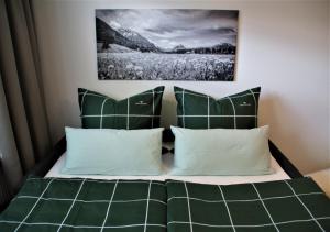 una camera da letto con letto, lenzuola e cuscini verdi di Ferienwohnung Almwiese a Oberstdorf