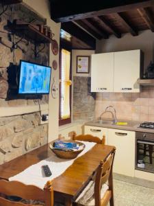 uma cozinha com uma mesa de madeira e uma televisão em Rustico San Jacopo em Gallicano