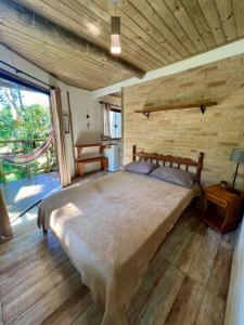 ein Schlafzimmer mit einem großen Bett und einer Ziegelwand in der Unterkunft Hospedagem Casa Maracujá in Trindade