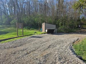 a dirt road with a sign next to a shed at Cardinal Cove Campsite at Hocking Vacations - Tent not included in Logan