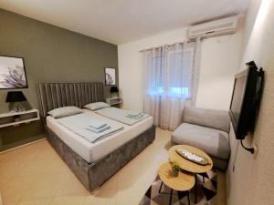 a bedroom with a bed and a couch and a television at RUBIS SUITE in Mostar