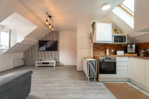 a kitchen with white cabinets and a couch in a room at Logement 7 personnes près de Disney & Paris in Chanteloup-en-Brie