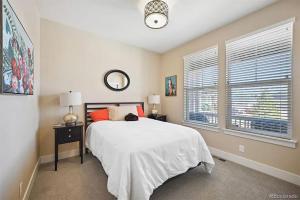 a bedroom with a white bed and two windows at 4BR Home close to Airport in Aurora