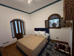 a bedroom with a bed and two windows at pyramids view Guest villa in Al Mazghūnah