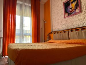 Schlafzimmer mit einem Bett mit orangefarbenen Vorhängen und einem Fenster in der Unterkunft Casa Simonetta in Foligno