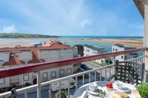 einen Balkon mit einem Tisch und Strandblick in der Unterkunft Apartamento Ría de Mogro in Mogro