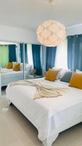 a bedroom with a large white bed with yellow pillows at Promo Viviendas Sol y Mar in Juan Dolio