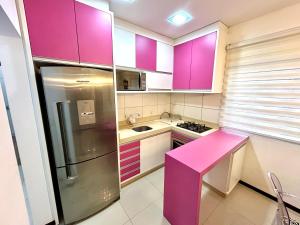 une cuisine avec des placards violets et un comptoir rose dans l'établissement Apartamento inteiro muito aconchegante, à Joinville