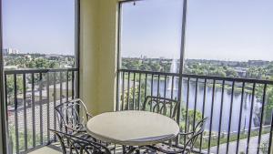 une table et des chaises assises sur un balcon avec fenêtres dans l'établissement Hilton Grand Vacation Club Tuscany Village, à Orlando