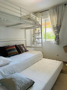 1 dormitorio con 2 camas y ventana en Apartamento 100m2 con piscina y jardín para 6 personas en Cambrils, en Cambrils