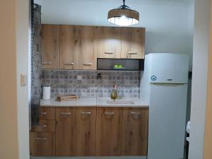 a kitchen with wooden cabinets and a white refrigerator at Kanela House in Nea Kalikratia