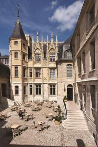 un grande edificio con tavoli e sedie in un cortile di Hôtel de Bourgtheroulde, Autograph Collection a Rouen