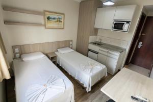a small room with two beds and a kitchen at Hotel Golden Star in Curitiba