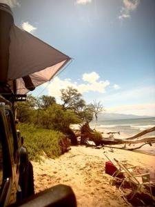 a vehicle parked on a beach with an umbrella at Embark on a journey through Maui with Aloha Glamp's jeep and rooftop tent allows you to discover diverse campgrounds, unveiling the island's beauty from unique perspectives each day in Haiku