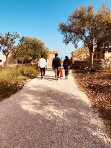 a group of people walking down a gravel road at Casa Imayah in Noto