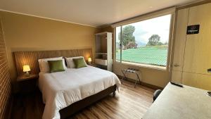 ein Hotelzimmer mit einem Bett und einem großen Fenster in der Unterkunft Di Carbone Hotel Gastrobar in Facatativá