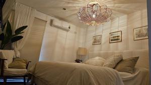 a bedroom with a white bed and a chandelier at Finca Las Margaritas in Santiago del Estero