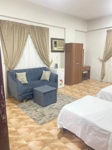 a living room with a blue couch and a bed at اجنحة التميز للوحدات السكنية in Medina