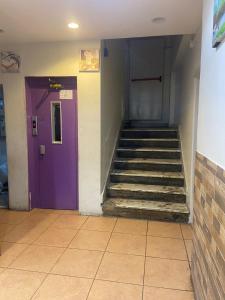 a hallway with a purple door and stairs in a building at اجنحة التميز للوحدات السكنية in Medina