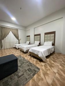 a bedroom with two beds and a table in it at اجنحة التميز للوحدات السكنية in Medina
