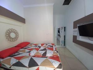 OYO 93962 Jm Guest House في Pundong: غرفة نوم بسرير وتلفزيون بشاشة مسطحة