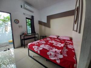 um quarto com uma cama vermelha e branca com almofadas cor-de-rosa em OYO 93962 Jm Guest House em Pundong