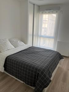 Appartement cosy à Bron في برون: غرفة نوم بسرير وبطانية بيضاء وسوداء