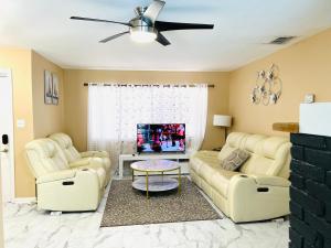 a living room with two couches and a tv at Pool house near beach in West Melbourne